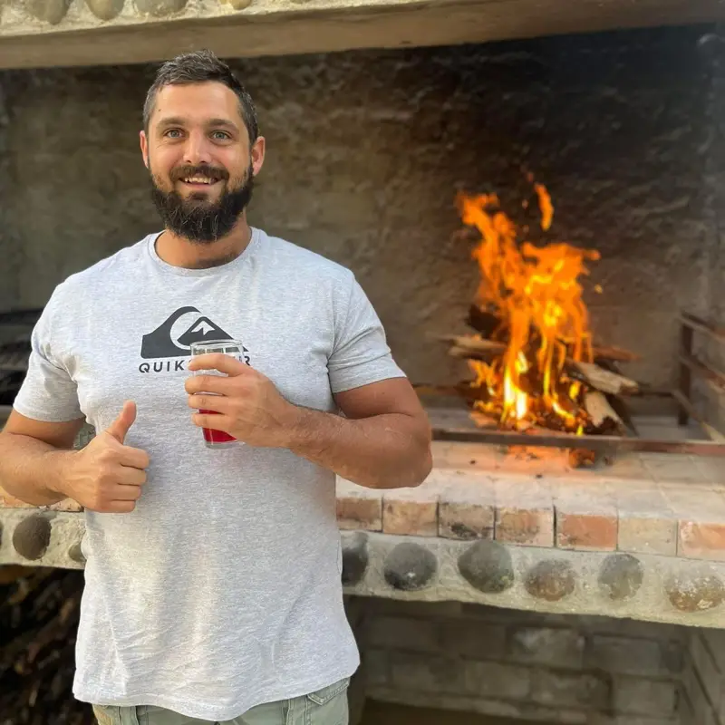 Boeta Louw, smiling, beside an open fire