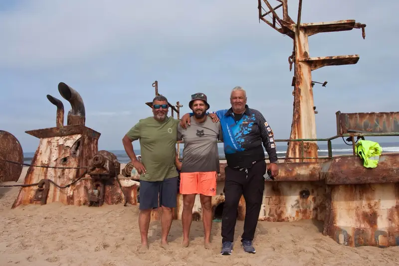 Boeta Louw (centre) with two other anglers on a rusted shipwreck on the beach